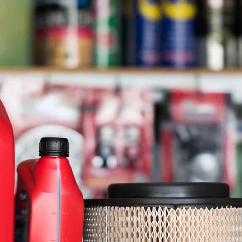 Red automotive oil bottles with black caps on store shelf, automotive maintenance supplies, vehicle oil containers.