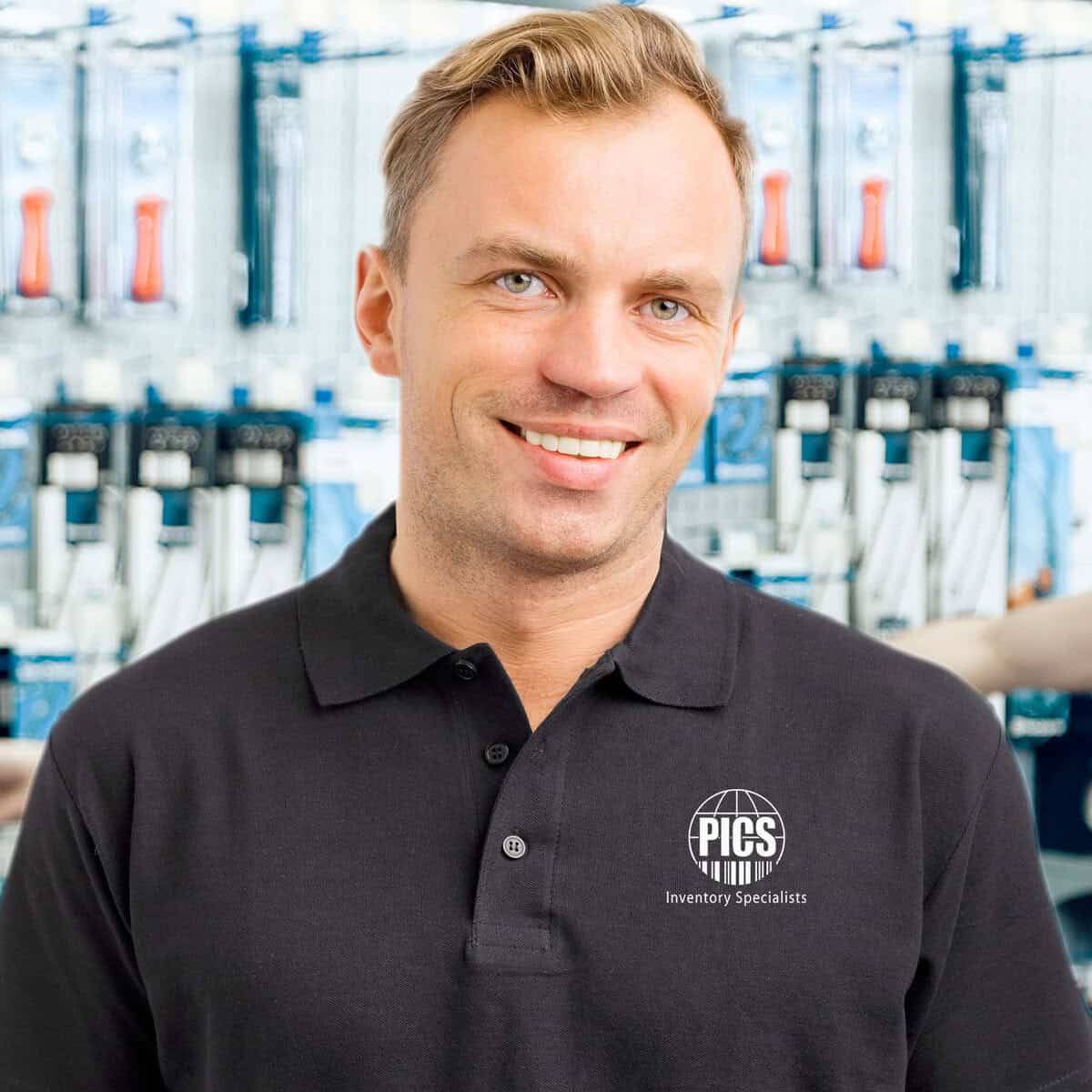 Inventory specialist smiling in a hardware store with tools in the background.
