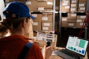 Accurate inventory management in a warehouse using barcode scanner, laptop, and stock shelves, ensuring efficient supply chain operations and optimized stock control.